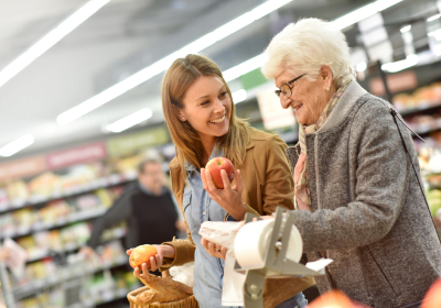 Caregiver helping elderly woman in a grocery store